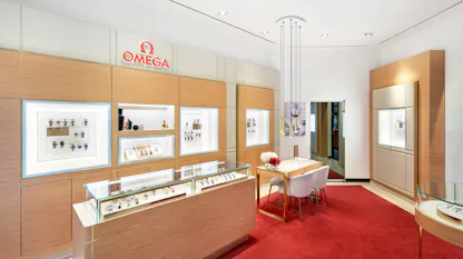 Interior of Omega boutique with red carpet, wood display cases, and illuminated wall showcases