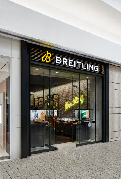 Exterior storefront of Breitling boutique at The 1916 Company with illuminated signage and glass entrance