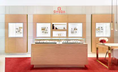 Omega watch showroom featuring central wood display counter and framed brand visuals