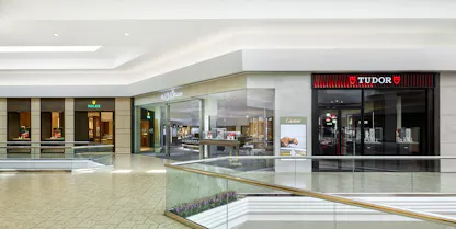 Wide view of The 1916 Company Denver storefront in the mall, flanked by the Rolex entrance on the left and the TUDOR boutique on the right.