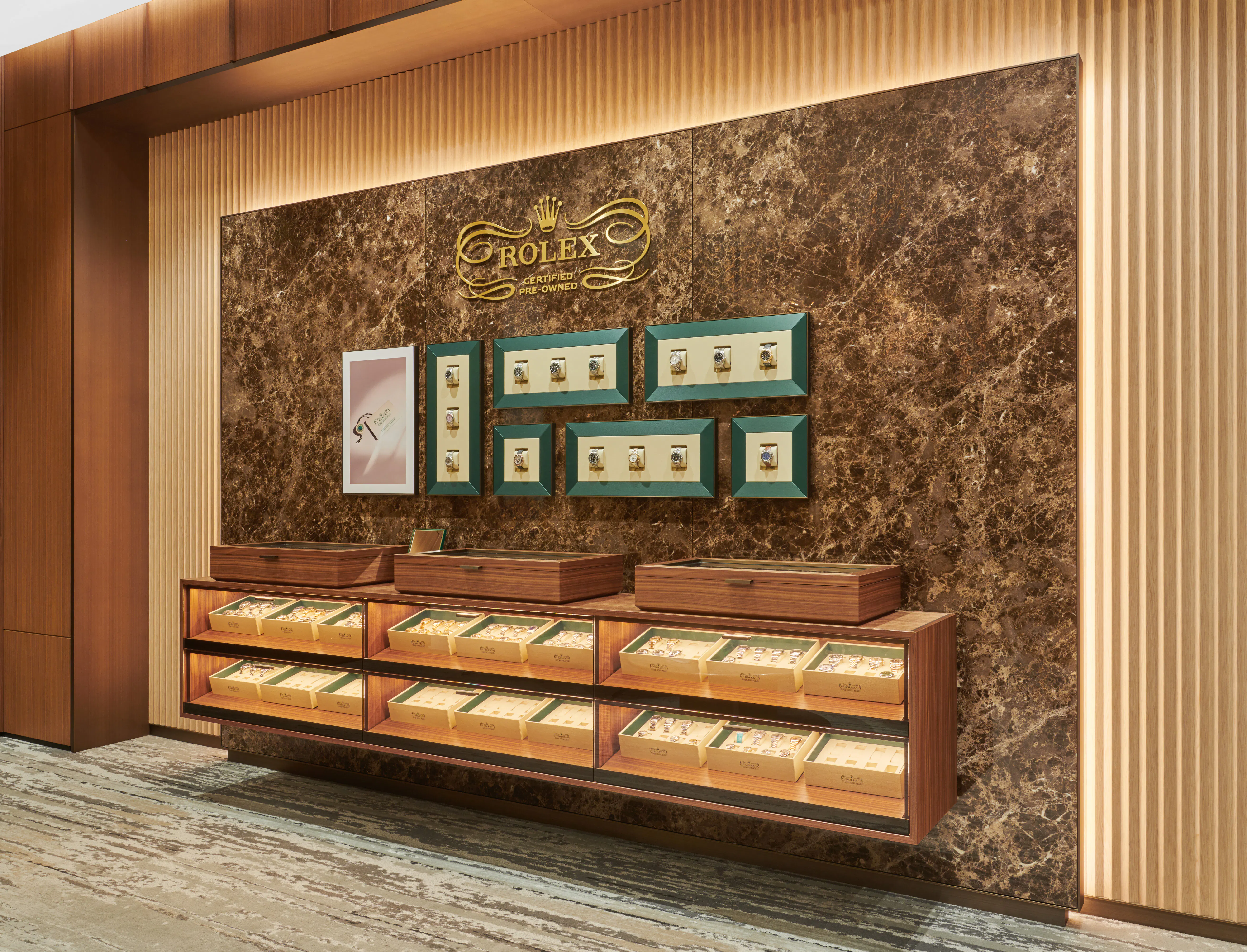Rolex Certified Pre-Owned watch display wall with green-framed watch cases and illuminated wood display cases at The 1916 Company