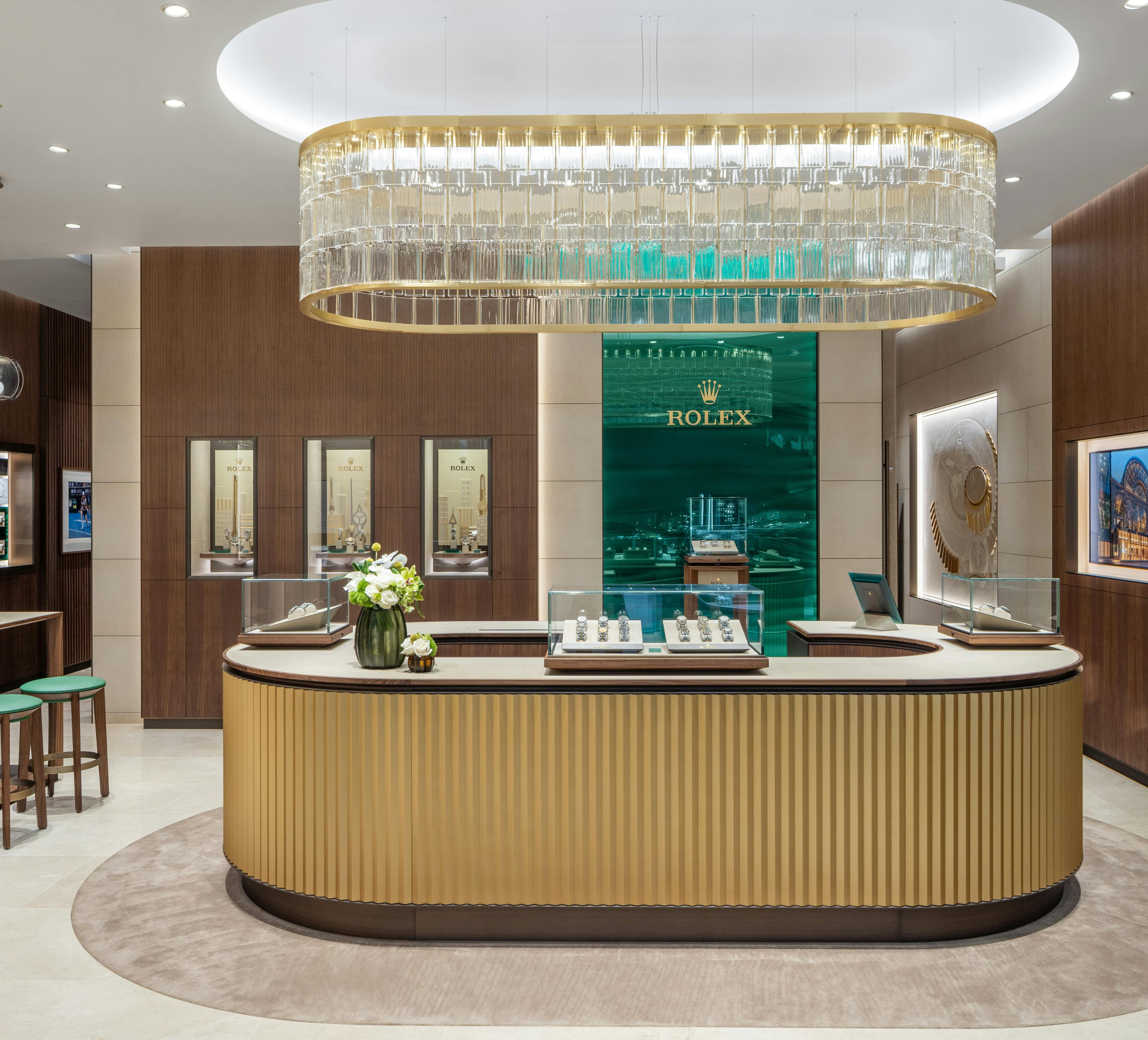 Interior of The 1916 Company Ardmore showroom featuring a Rolex display with gold counters and a chandelier.