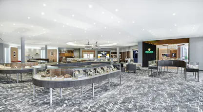 A spacious and upscale jewelry store showroom with numerous curved glass display cases filled with jewelry. A large Rolex boutique entrance is visible on the right, and comfortable seating areas are scattered throughout the space.