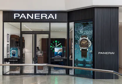Panerai boutique interior with illuminated wall clock, seating area, and watch display cases