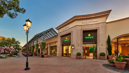 The 1916 Company Rolex authorized dealer exterior at Fashion Island Newport Beach with illuminated storefront at dusk
