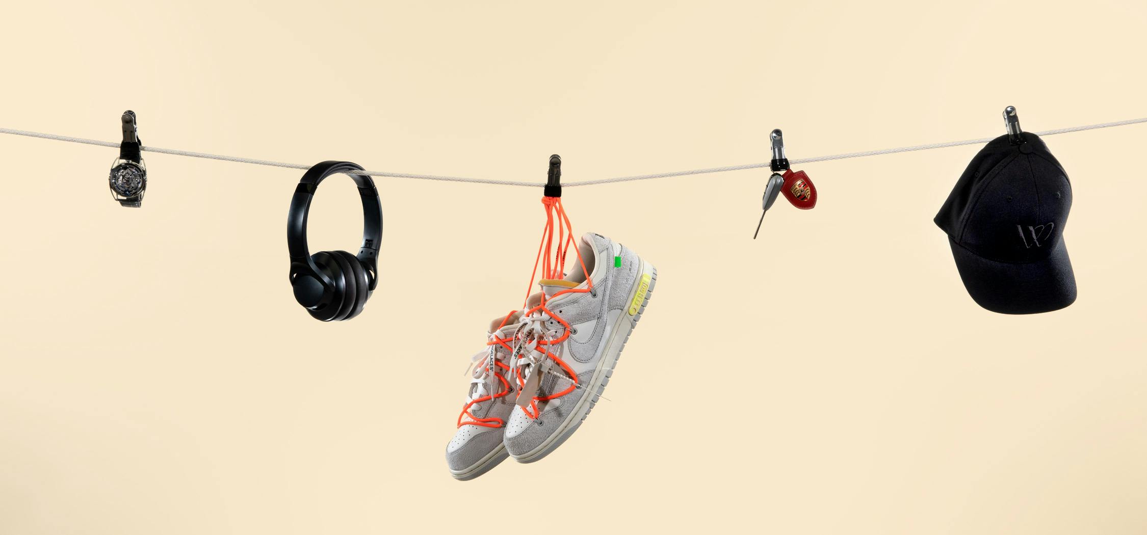 Watch, headphones, sneakers, car keys, and WatchBox hat hanging from a clothesline